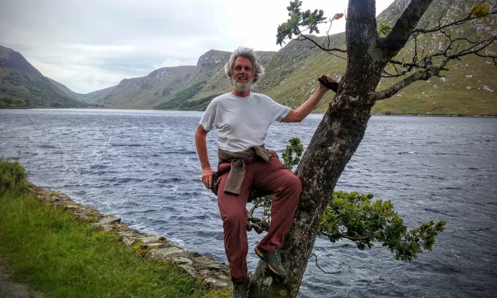 A picture of Michael Kalyaano sitting on a tree branch at the Glenveagh National Park, Donegal, Ireland in 2016